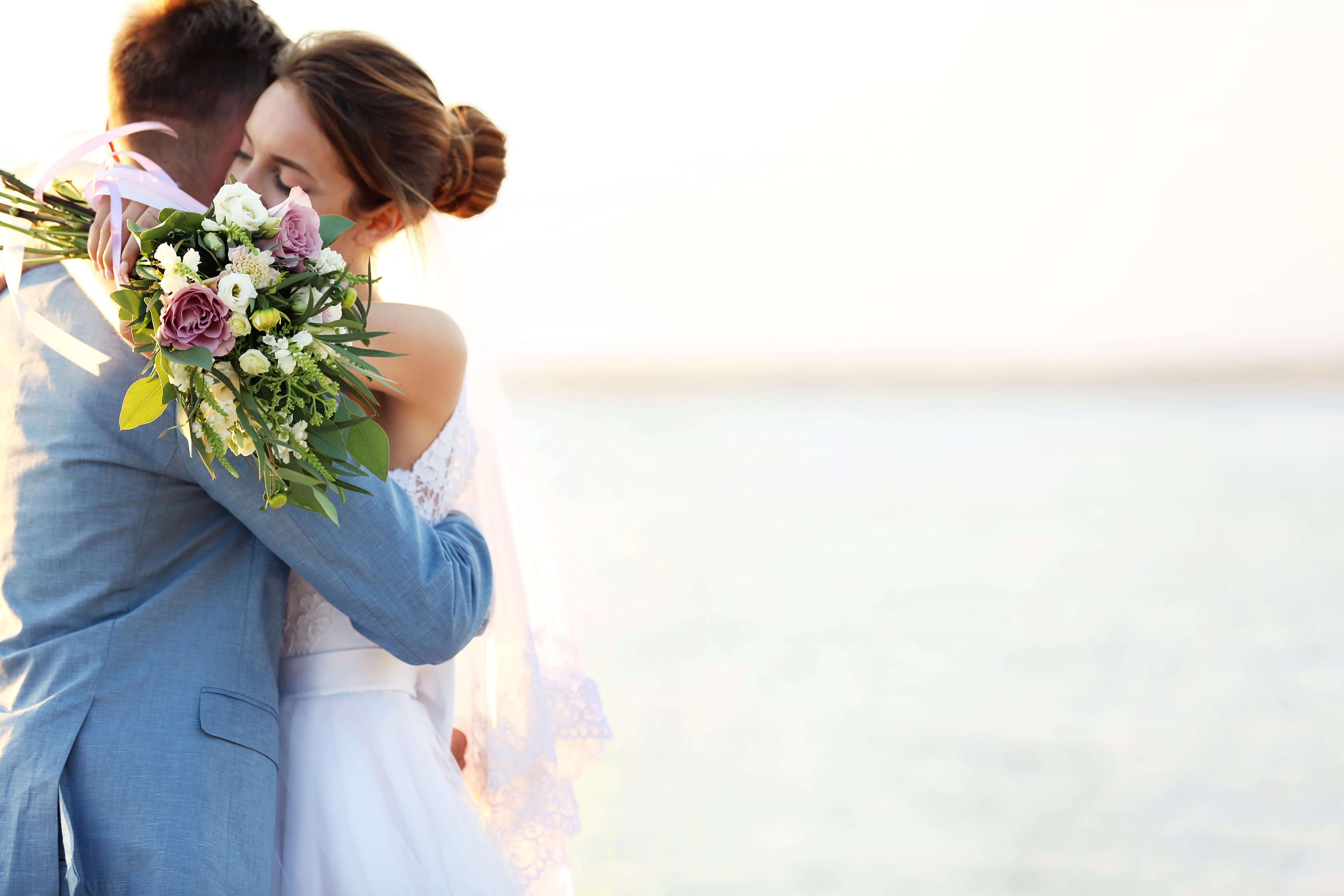 Couple embracing at sunset with a rose bouquet at Coquina Beach